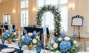 Elegancka dekoracja sali weselnej w odcieniach niebieskiego. Kwiatowe łuki i bukiety tworzą magiczną atmosferę.