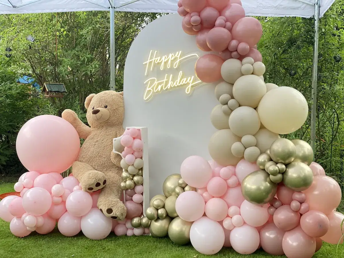 Urocza dekoracja na 1 urodziny dziewczynki: wielki miś, balony w pastelowych kolorach i neonowy napis 